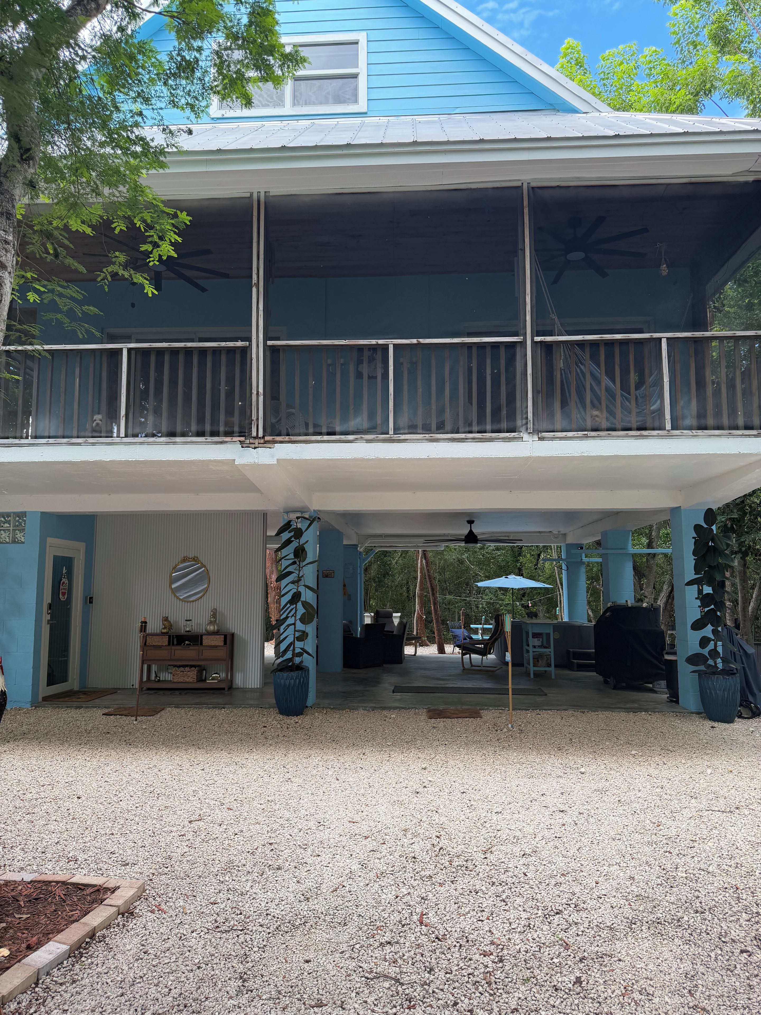 A two-story house with a covered porch, a dining area, and a barbecue setup.
