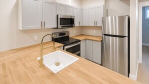 Eine moderne Küche mit weißen Schränken, Edelstahlgeräten und einer Holzausziehtafel.