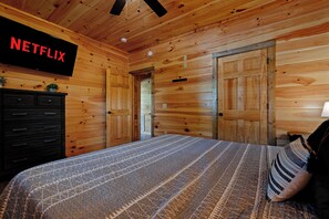 Una habitación con paneles de madera, una cama, un aparador y una puerta.