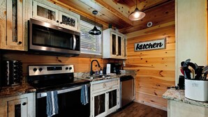 Eine Küche mit Holzwänden, einer Mikrowelle, einem Herd, einem Backofen und einem Schild mit der Aufschrift 'Kitchen'.