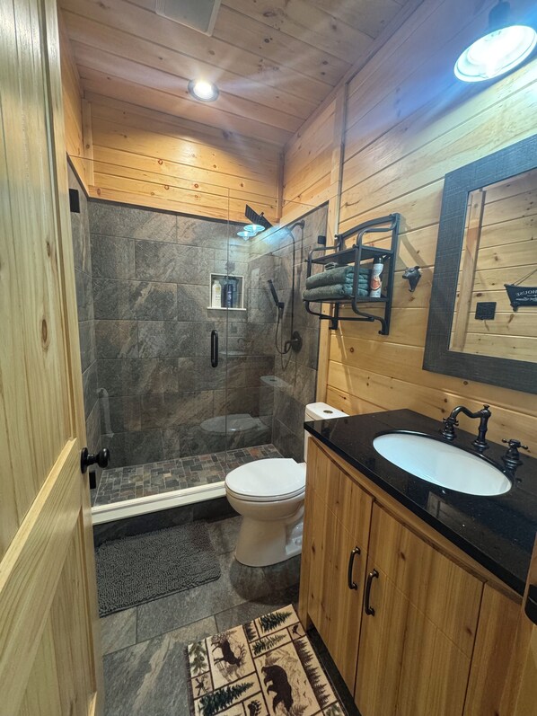 Een badkamer met douche, toilet, wastafel en houten kastjes.