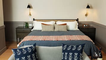 A bedroom with a bed, a sofa, two bedside tables, and a lamp.