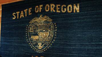 A wall with the text 'STATE OF OREGON 1859' and a coat of arms.