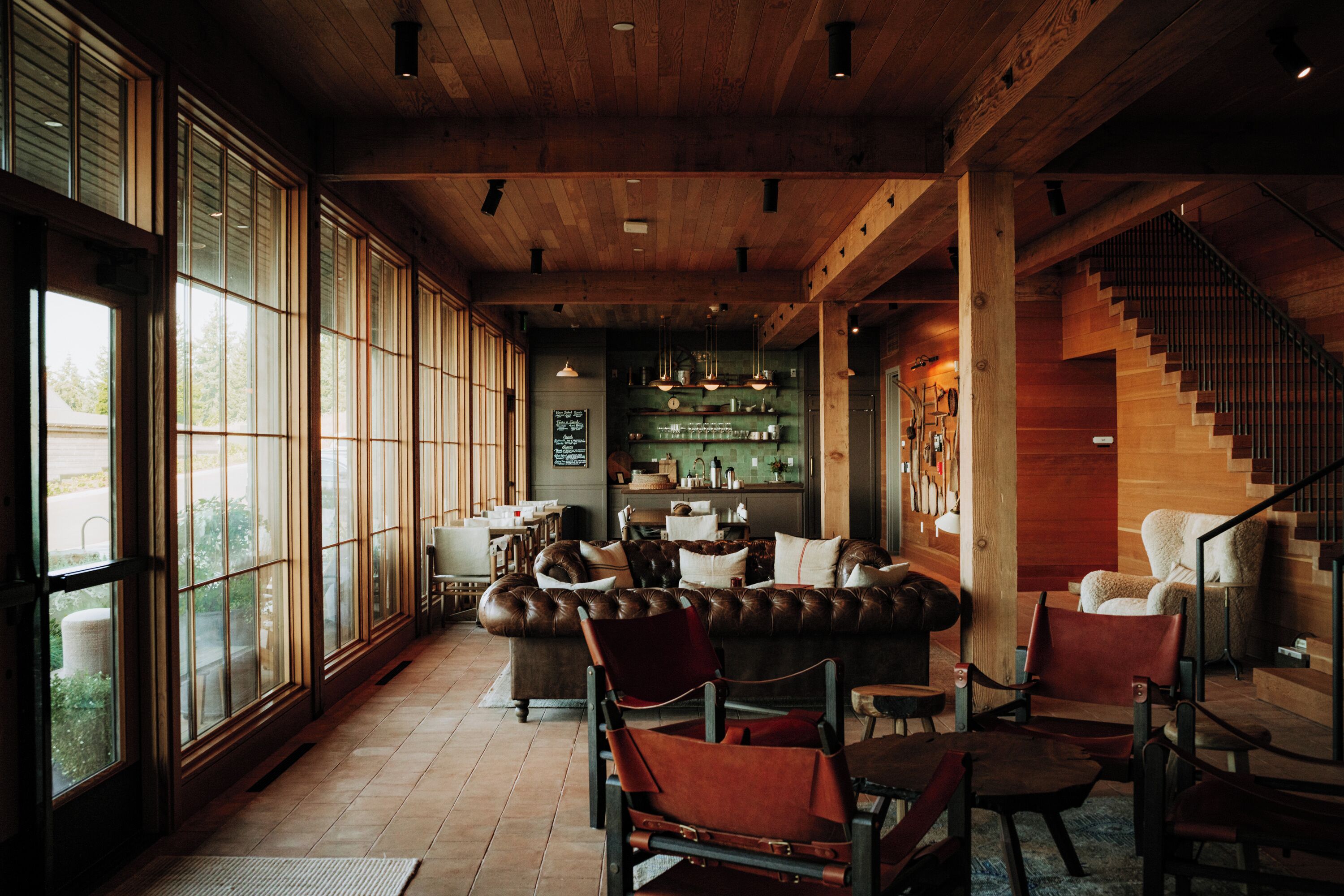 A spacious living area with a large window, a leather sofa, and a staircase.