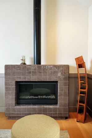 Una chimenea con un revestimiento de baldosas, una escalera de madera y una alfombra tejida.
