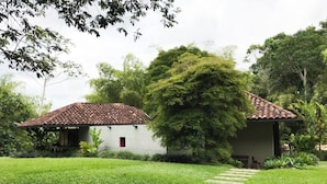 A house with a tiled roof, surrounded by a well-maintained lawn and a stone pathway leading to the entrance.