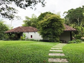A house with a tiled roof, surrounded by a well-maintained lawn and a stone pathway leading to the entrance.