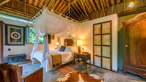 A room with a bed, a nightstand, a wooden cabinet, a cowhide rug, and a canopy bed.