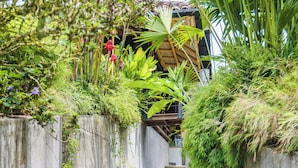 A concrete staircase flanked by lush greenery, leading to a building with a wooden structure.