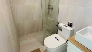 Un baño moderno con ducha de vidrio, inodoro y lavamanos.