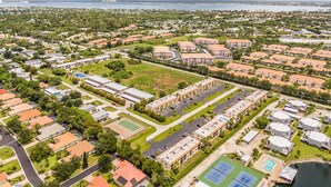 Zona residencial con varios edificios de apartamentos, un campo deportivo y una masa de agua al fondo.