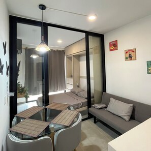 A modern room with a glass dining table, a sofa, and a bed. - Apartment in Santa Marta | 5-minute drive from the beach (Santa Marta)