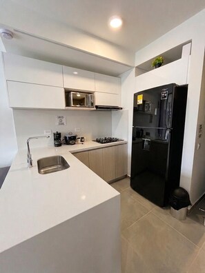Een moderne keuken met een ingebouwde kookplaat, een spoelbak en een zwarte koelkast.