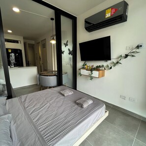 Ein modernes Schlafzimmer mit einem Bett, einem an der Wand befestigten Fernseher und einer Wandklimaanlage.
