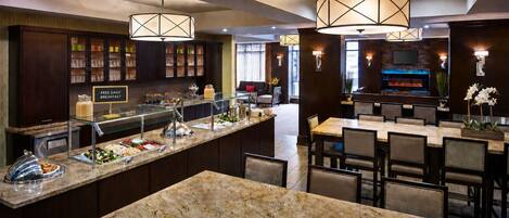 Un comedor de hotel con bufé, mesas y una barra.