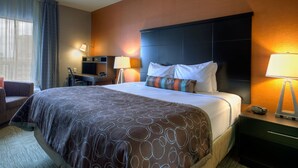 Ein Hotelzimmer mit Bett, Schreibtisch, Stuhl, Lampe und Nachttisch.