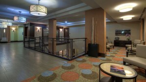 Eine Hotelhalle mit Holzboden, Glastrennwand, einer Sitzecke mit Tisch und einer Treppe.