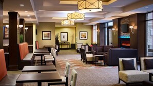 A hotel lobby with seating areas, a fireplace, and wall-mounted televisions. - Multi-Room Suite w/ Full Kitchen | Free Breakfast (Hamilton)