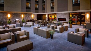 A spacious outdoor seating area with wicker furniture and stone walls. - Multi-Room Suite w/ Full Kitchen | Free Breakfast (Hamilton)