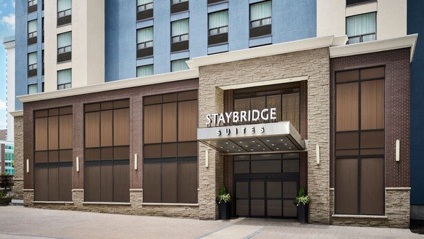 Ett Staybridge Suites-hotell med en modern fasad, stora fönster och en framträdande entré.