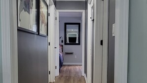 Ein Flur mit Holzboden, weißen Wänden und einem Deckenventilator.