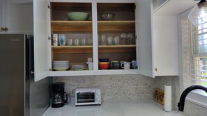 A kitchen with a built-in microwave, a coffee maker, and a toaster oven.