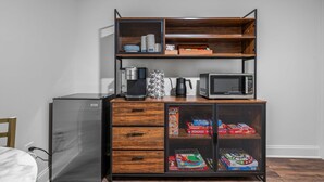 A kitchenette with a coffee maker, microwave, and storage cabinets containing board games. - Sabel #201 | Downtown Asheville king suite with parking, Wi-Fi, and smart TV. (Asheville)
