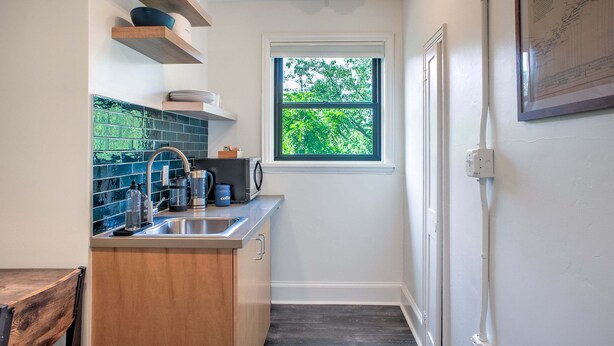 A compact kitchen with a window, a sink, and a coffee maker. - Sabel #201 | Downtown Asheville king suite with parking, Wi-Fi, and smart TV. (Asheville)
