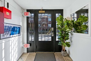 A black door with two EXIT signs, a StarLink box, a security camera, and a potted plant. - Sabel #302 | Downtown Asheville king suite with Wi-Fi, parking, and mini kitchen. (Asheville)