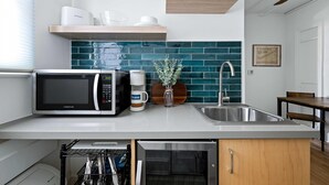 Una cocina moderna con microondas integrado, cafetera y pileta.