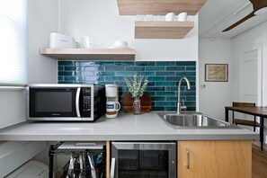 A modern kitchen with a built-in microwave, coffee maker, and a sink. - Sabel #302 | Downtown Asheville king suite with Wi-Fi, parking, and mini kitchen. (Asheville)