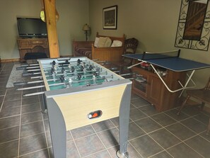 Ein Fußballtisch in einem Raum mit Fernseher, einem Bett und einem gerahmten Bild an der Wand.