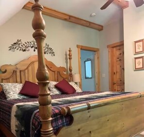 Ein Schlafzimmer mit einem Holzbettgestell, einem Kopfende mit dekorativer Gestaltung und einer Tür im Hintergrund.
