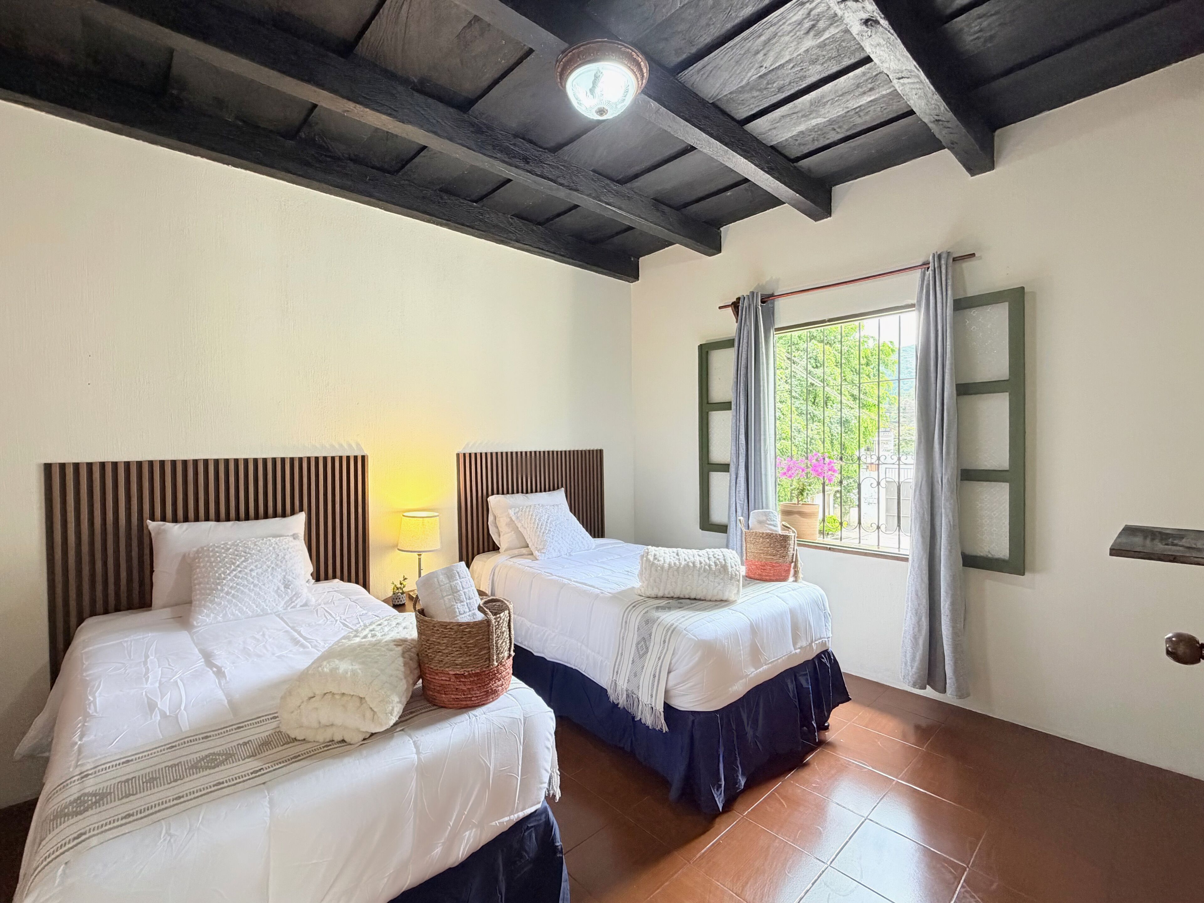 Una habitación con dos camas, una ventana con vistas, un ventilador de techo y una lámpara.