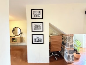 Habitació amb un armari de fusta, un mirall, una fotografia en blanc i negre amb marc, una cadira de pell marró i una planta en test.