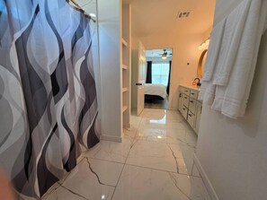 Une salle de bain avec un rideau de douche, un lit, un lavabo et un miroir.