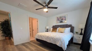 A bedroom with a bed, bedside tables, a ceiling fan, and a door leading to another room. - Modern OKC Duplex | Close to OU Med & Downtown (Oklahoma City)