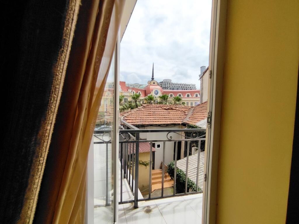 Vista desde una ventana que da a un edificio con tejados rojos y una torre central.