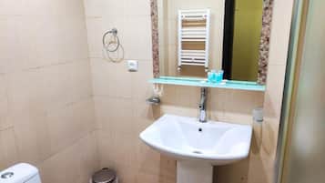 Un baño con un lavamanos blanco, un espejo, un perchero para toallas y un inodoro.