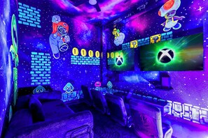 A gaming room with multiple gaming stations, neon lights, and various gaming-related decorations. - Gamer’s Den—Drive-In Cinema/Arcade/Outdoor Bowling (Pigeon Forge)
