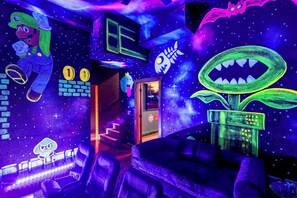 A room with a bed, a staircase, and walls decorated with space-themed artwork. - Gamer’s Den—Drive-In Cinema/Arcade/Outdoor Bowling (Pigeon Forge)