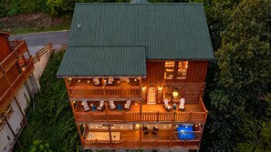 A multi-story log cabin with outdoor seating and a pool. - Gamer’s Den—Drive-In Cinema/Arcade/Outdoor Bowling (Pigeon Forge)