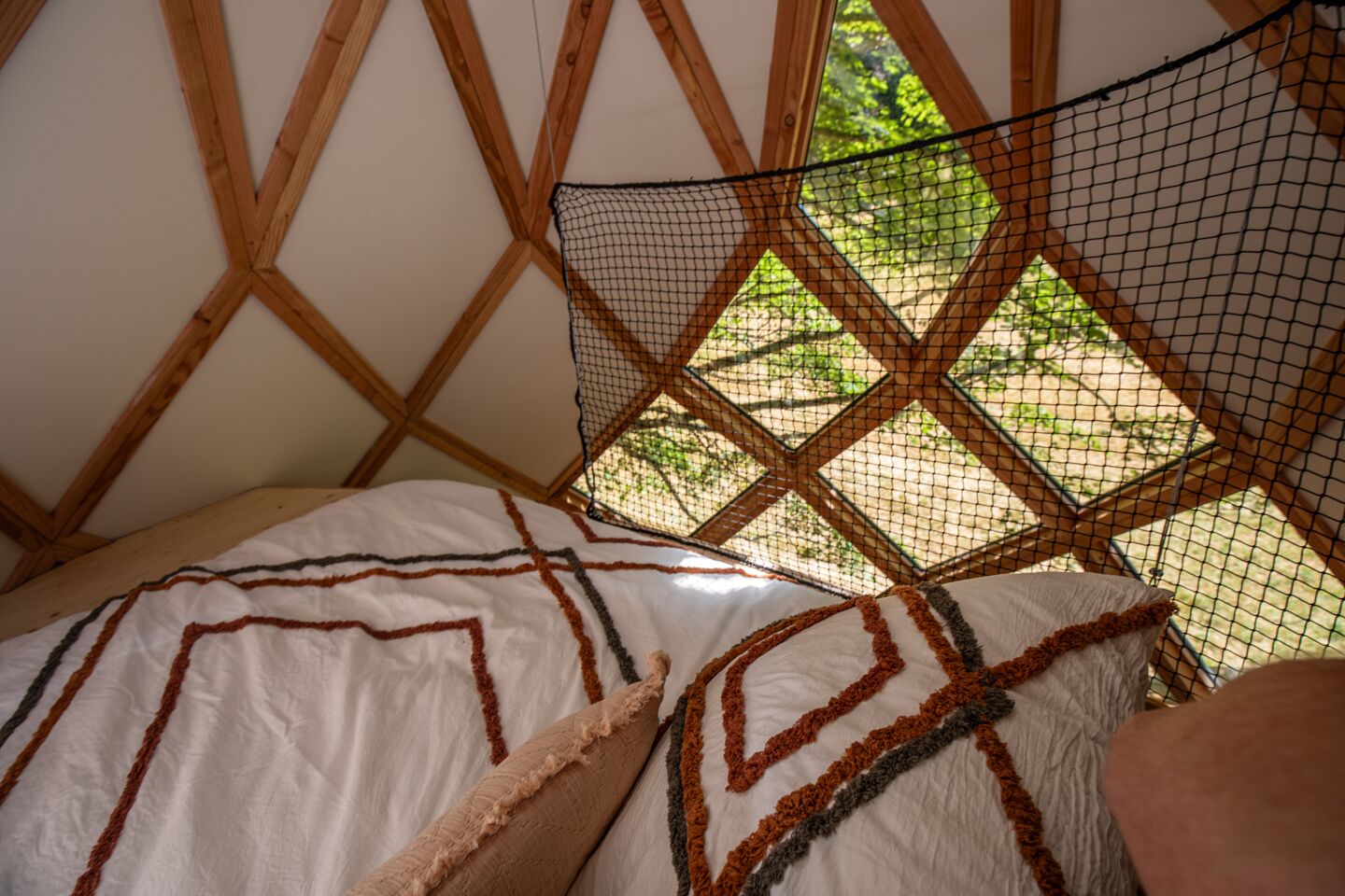 Een kamer met een bed, een vliegenhor en uitzicht op groen.