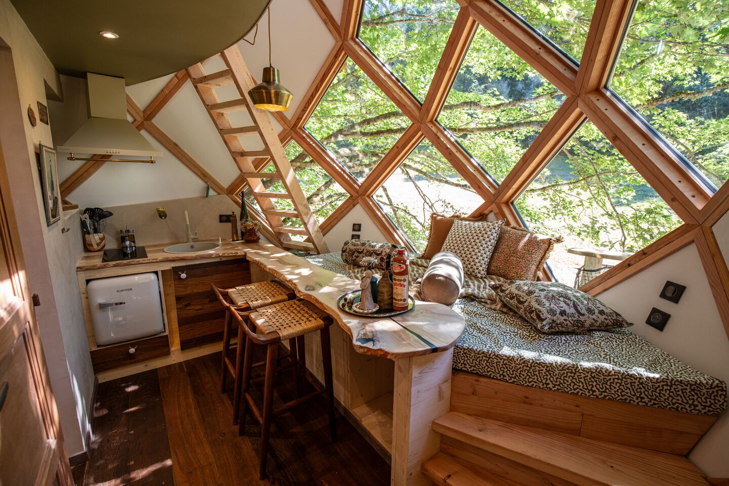 Een gezellig vakantiehuisje met een keuken, eethoek en een slaapvide met uitzicht op het bos.