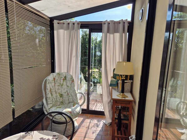 Una habitación con una silla, una lámpara y vista a través de un ventanal.