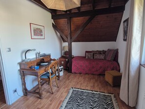 A bedroom with a wooden desk, a chair, a bed with patterned bedding, a zebra-patterned rug, and a ceiling fan. - Charmante maison à Sundhoffen classée 3 clés parfaite pour des séjours reposants (sundhoffen)
