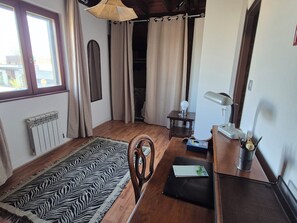 A room with a zebra-patterned rug, a wooden chair, a desk with a lamp, a radiator, and a window with curtains. - Charmante maison à Sundhoffen classée 3 clés parfaite pour des séjours reposants (sundhoffen)