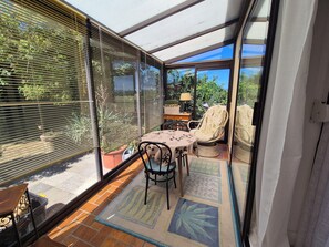 Una habitación iluminada por el sol con una mesa, sillas y una planta en maceta.