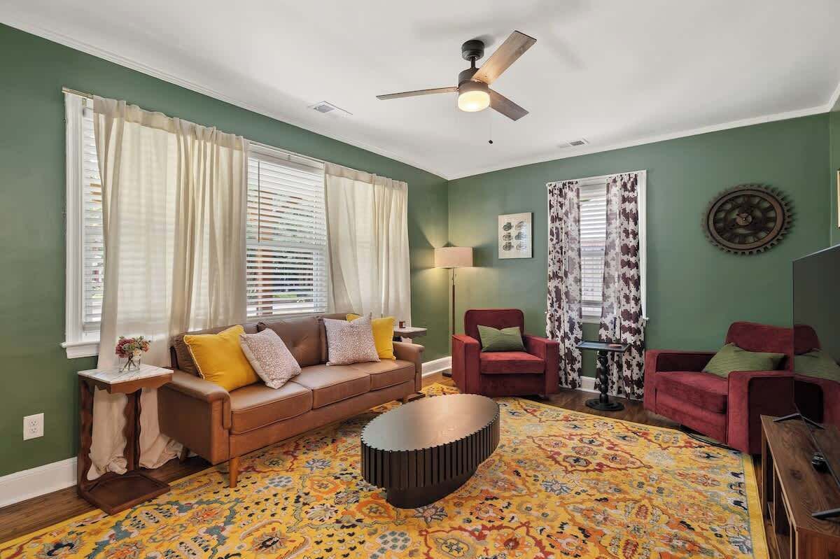 A living room with a brown sofa, red chairs, a round coffee table, and a patterned rug.