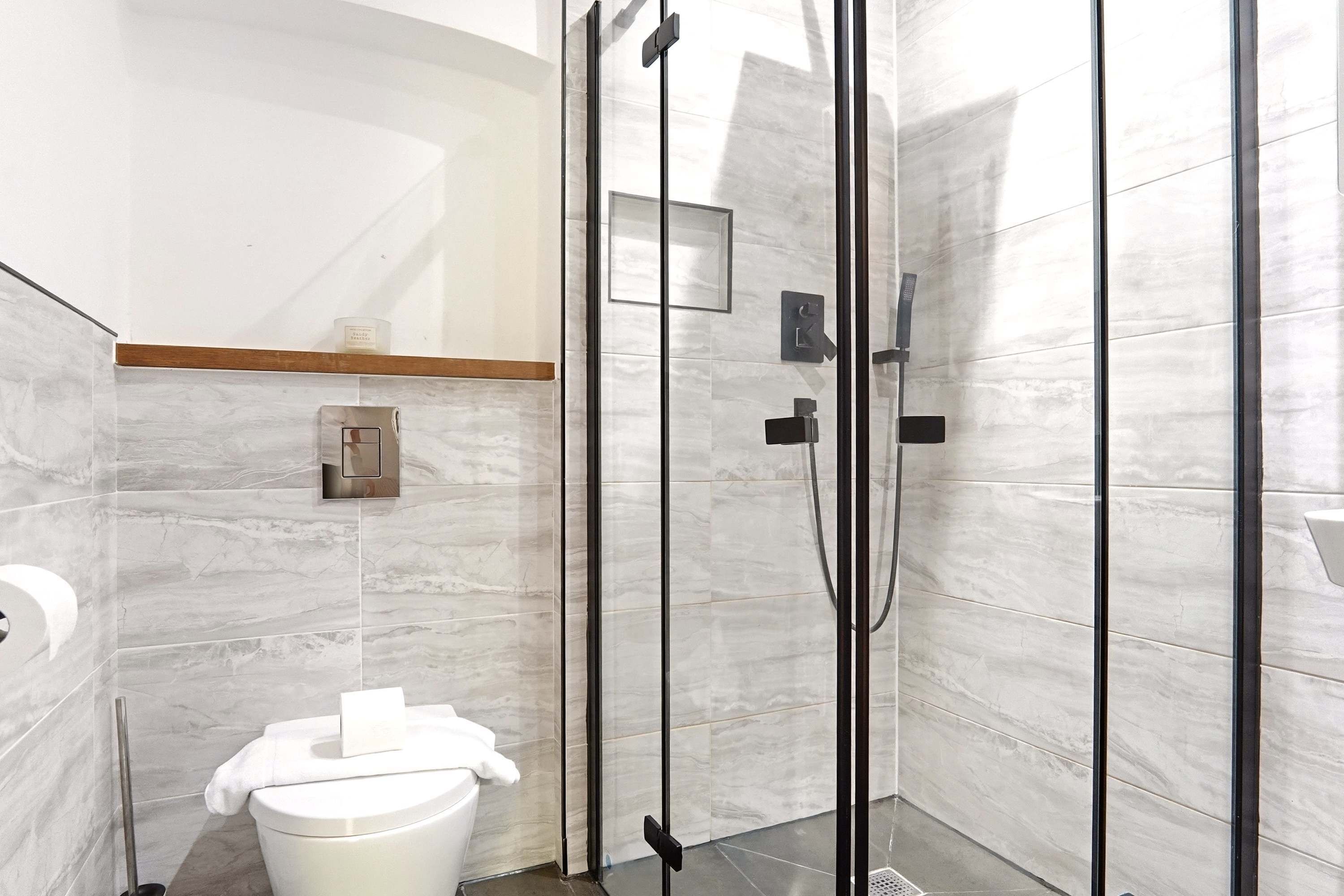 Un baño moderno con inodoro, cabina de ducha y un perchero para toallas.